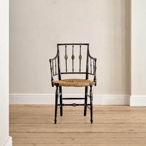 An ebonised and painted elbow chair