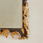 A rectangular mirror with an ebonised and parcel gilt carved frame