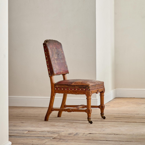 A Reformed Gothic oak upholstered side chair covered in the original red leather