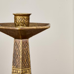 A pair of hexagonal brass candlesticks with geometric decoration