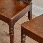 A pair of George IV oak hall chairs