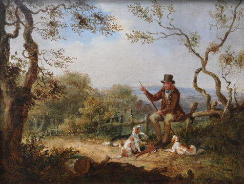 Sportsman reloading with spaniels and a pheasant at is feet